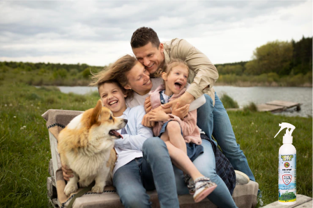 A family of four enjoying a windy day by the water with their dog. With an 8 oz bottle of Minus Bite All Natural Family Friendly bug spray on the table.