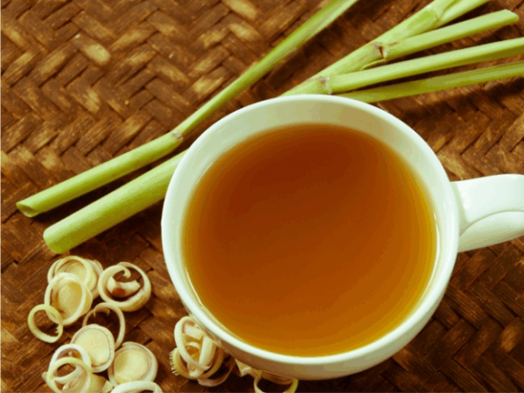 A full cup of fresh lemongrass tea with some fresh lemongrass plant stalks next to it. Drink up!
